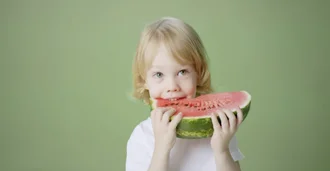 A young boy joyfully holds a slice of watermelon